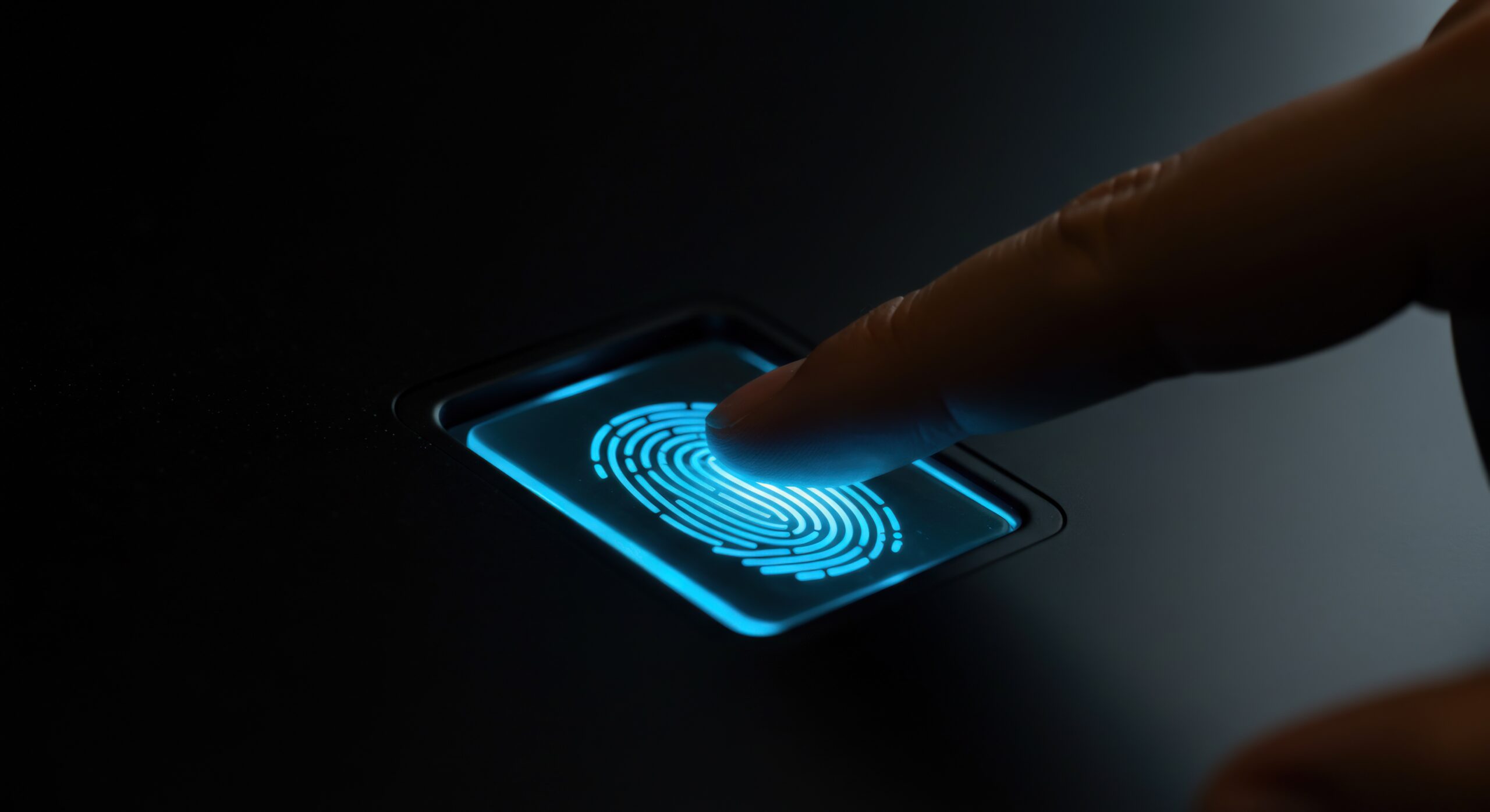 A finger touches a glowing blue fingerprint scanner, illustrating biometric authentication and data security. The composition emphasizes the fingerprint pattern and the act of scanning, set against a dark background. The image conveys themes of technology, protection, and digital identity. The visual style is modern, with a focus on clean lines and glowing accents. Suitable for representing security software, privacy solutions, identity verification, or innovative technology solutions, the image could be used in commercial or editorial contexts.